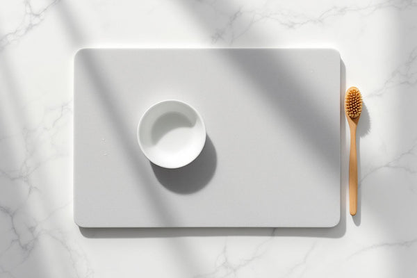 Eco friendly diatomite dish drying mat on marble countertop with ceramic bowl and wooden brush