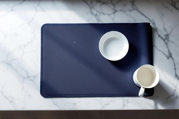 Eco friendly dish drying mat in navy blue on a marble kitchen counter with ceramic dishes