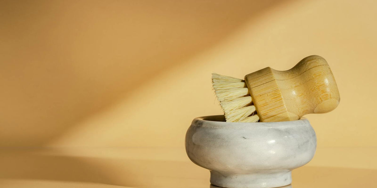 Bamboo scrub brush in a marble bowl, minimalist kitchen aesthetic
