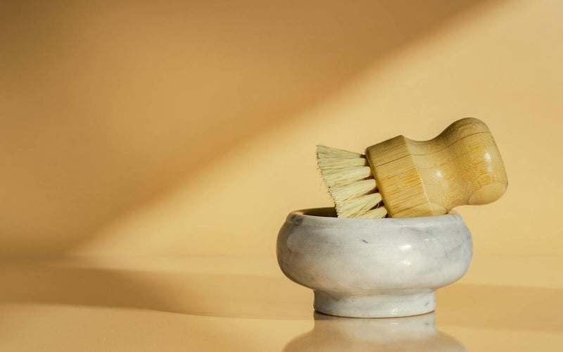 Bamboo scrub brush in a marble bowl, minimalist kitchen aesthetic