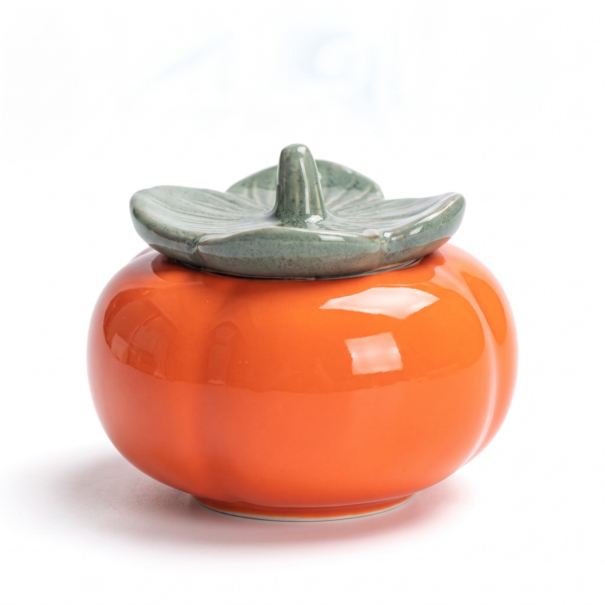 ceramic tea caddy — persimmon jar with sage-green leaf lid on white