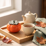 ceramic tea caddy — persimmon jar on a tea tray beside a teapot and cup