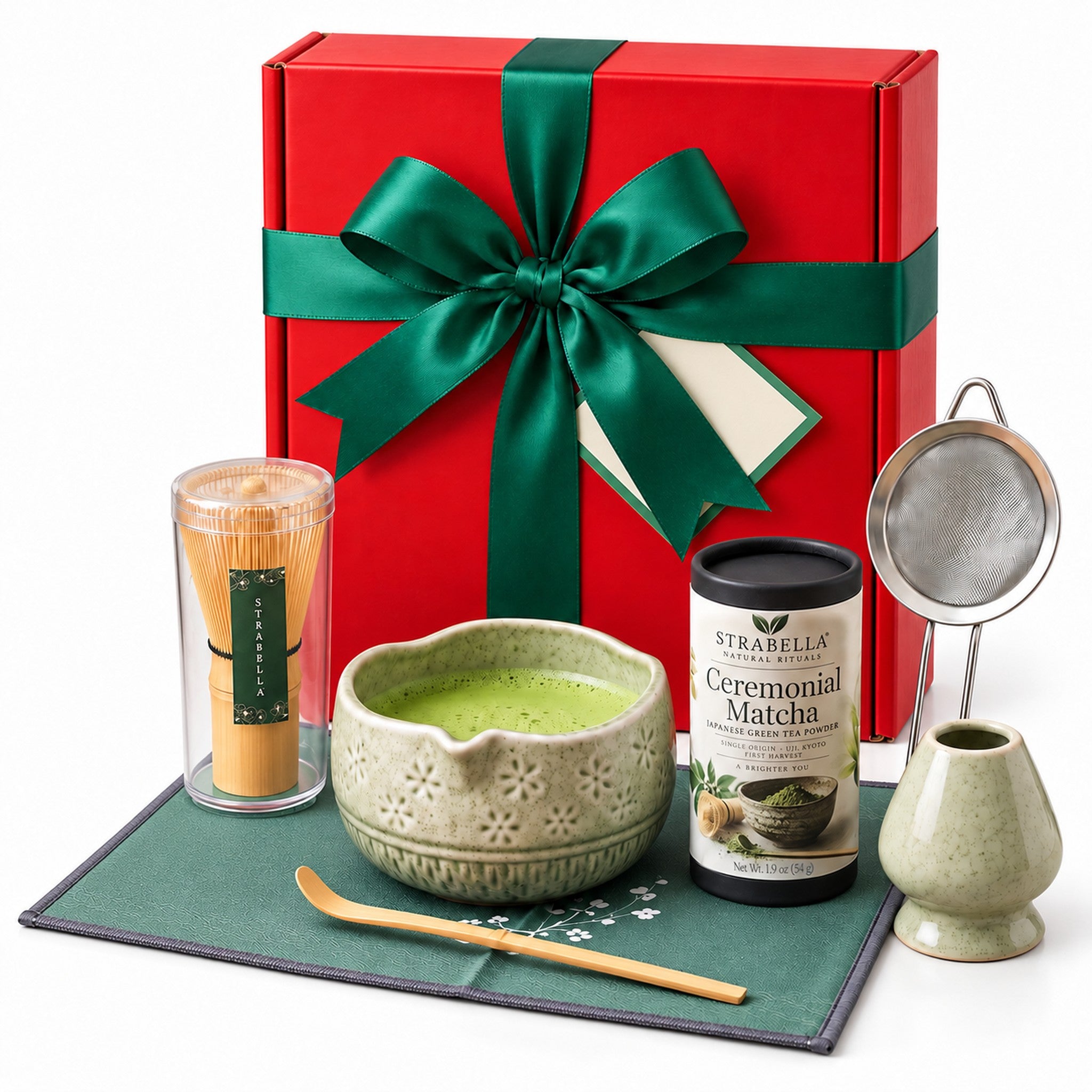 Christmas Matcha Gift Box, Green: red gift box with a green satin bow standing behind the green 7-piece matcha whisk set and Ceremonial Matcha tin