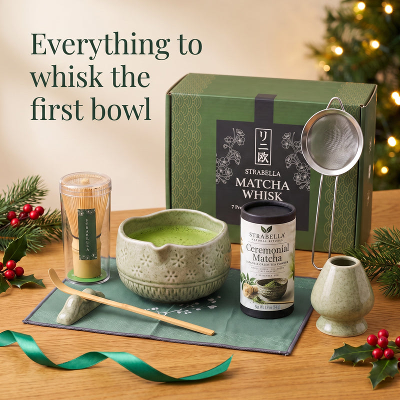 Green 7-piece matcha whisk set with bamboo chasen, ceramic chawan, holder, scoop, sifter and mat, next to the 54 g ceremonial matcha tin