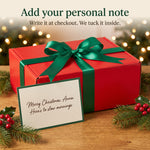Personal Christmas note card in front of the red gift box with a green satin bow