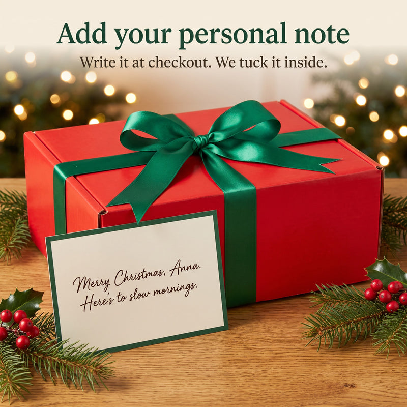 Personal Christmas note card in front of the red gift box with a green satin bow
