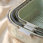 colander with bowl detail — drainage holes and silver handles on the mint green set