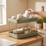 Countertop mug rack in use — hand setting a rinsed mug upside down to drain on the top tier