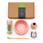 Flat lay of the pink Strabella Hojicha Set — ceramic bowl, bamboo whisk, holder, scoop and stone-milled hojicha powder