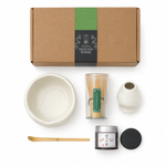 Flat lay of the white Strabella Hojicha Set — ceramic bowl, bamboo whisk, holder, scoop and stone-milled hojicha powder