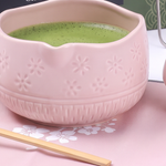 Pink ceramic matcha bowl with embossed sakura pattern and whisked matcha