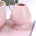 Pink ceramic whisk holder beside the matcha bowl