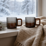 Two smoke-gray Strabella glass coffee mugs with wood handles on a snowy windowsill