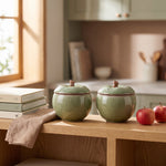 Apple trinket jars — light green pair on a kitchen shelf next to red apples